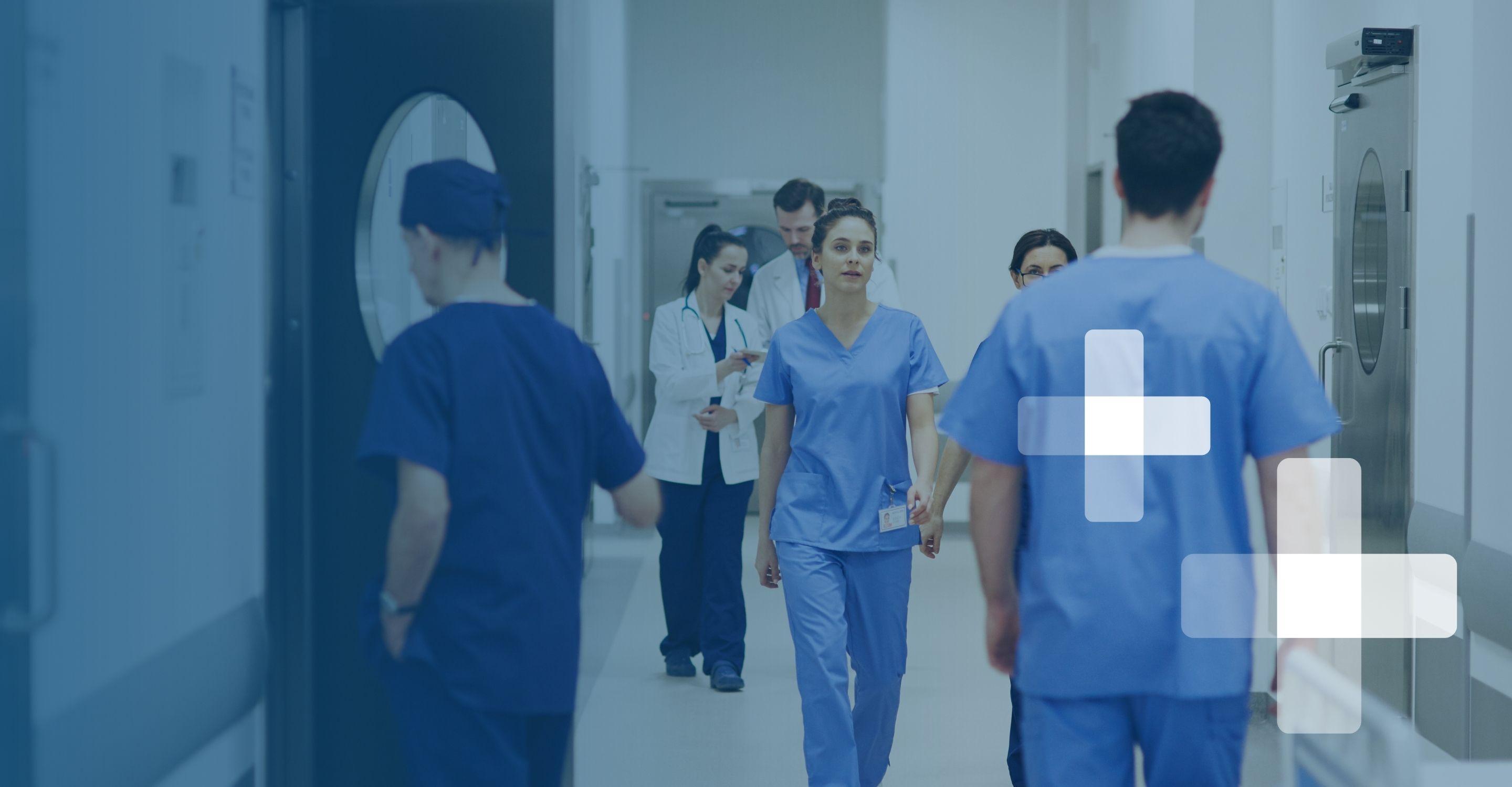Healthcare professionals walk calmly down a busy hospital hallway