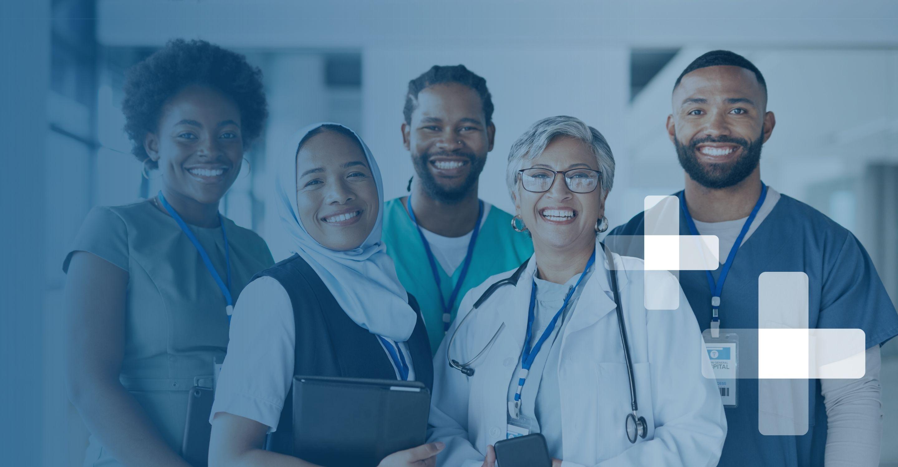 Five healthcare professionals stand together in professional attire, smiling at the camera