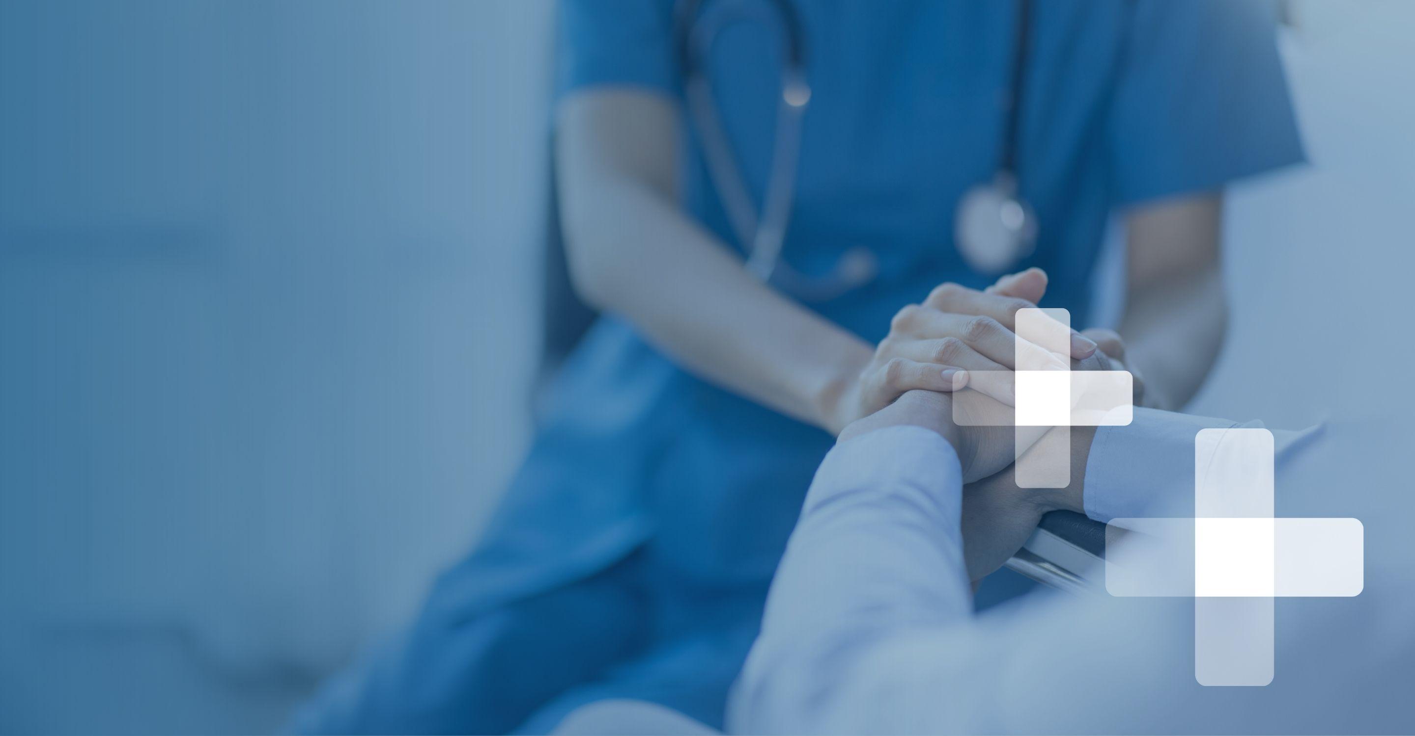 Close up photo of a person in scrubs holding the hands of an older person in white