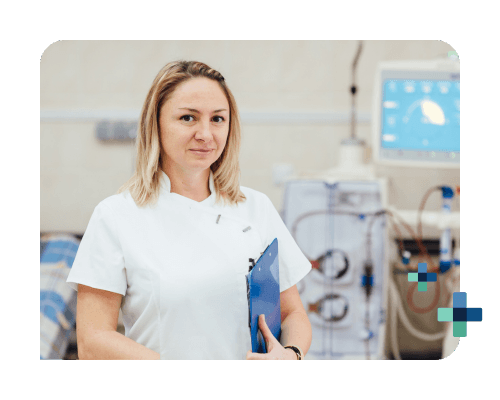 A young female dialysis tech stands in front of the dialysis machine with a clipboard