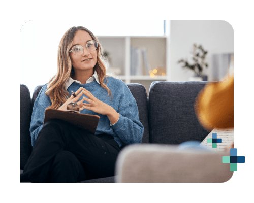 Counselor takes notes while two people sit close, holding hands in a session.