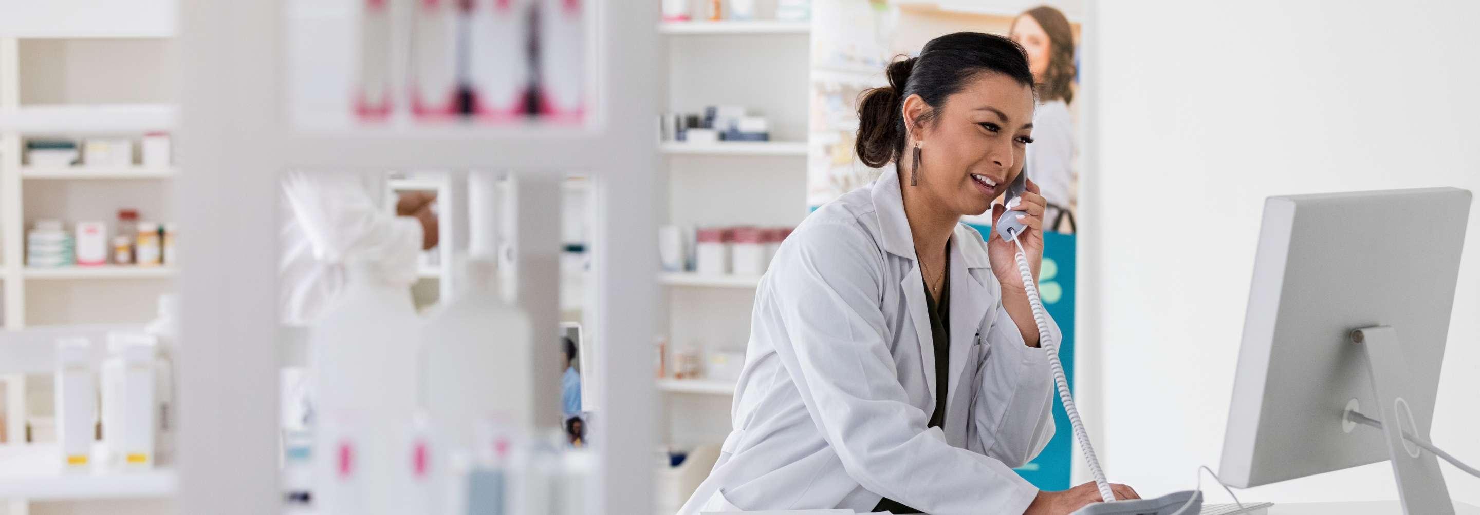 Pharmacy coordinator speaking with someone on the phone at the pharmacy counter