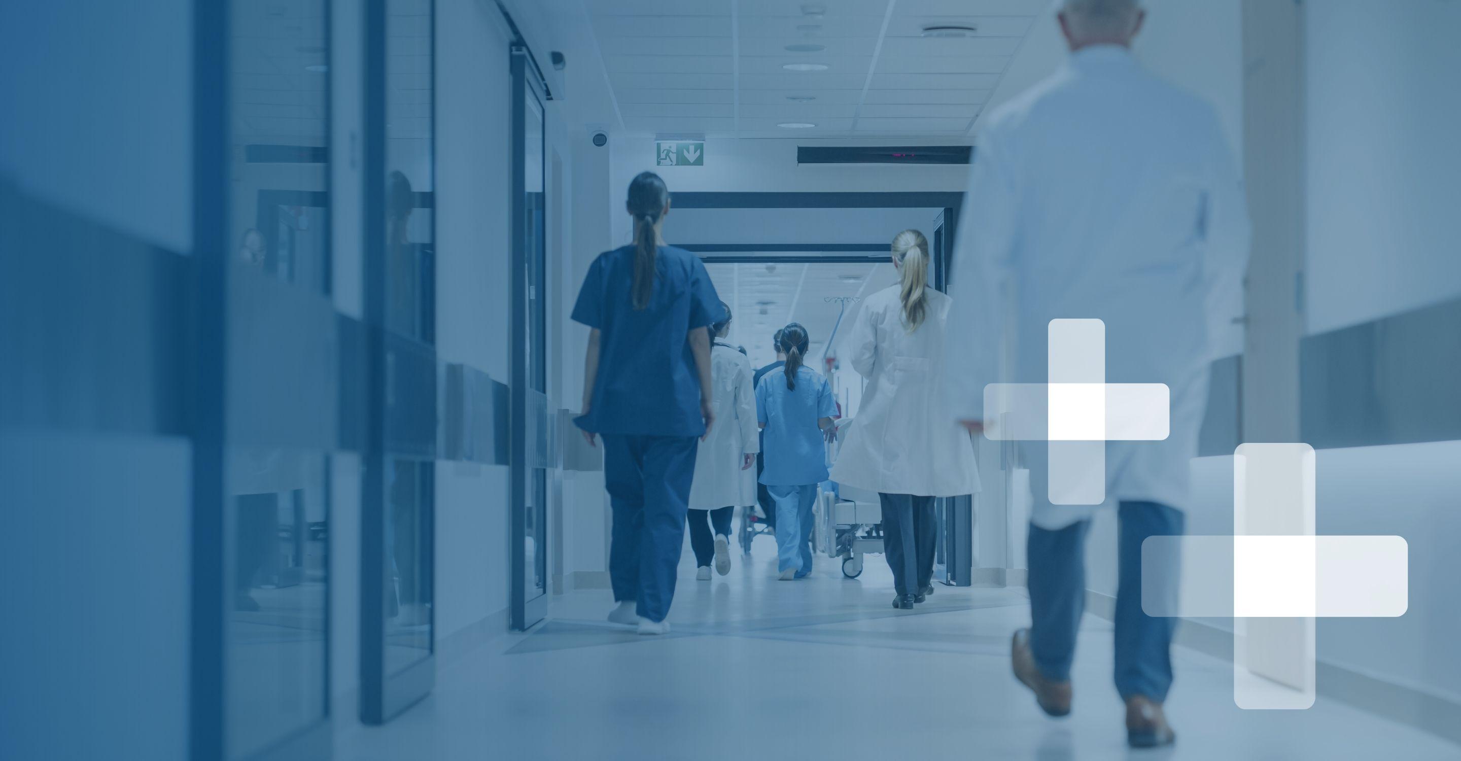 Photo of several healthcare professionals at a distance, walking down a hospital hallway