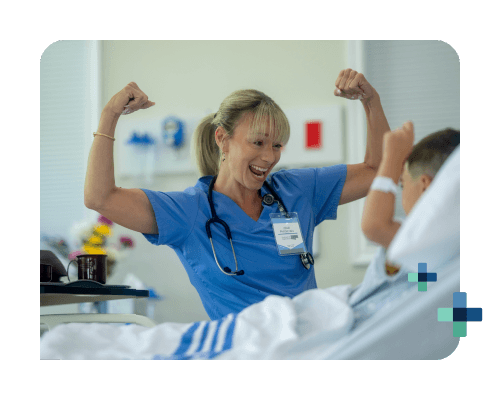 A smiling female nurse raises her arms in a sign of strength to cheer up a child at the hospital bedside