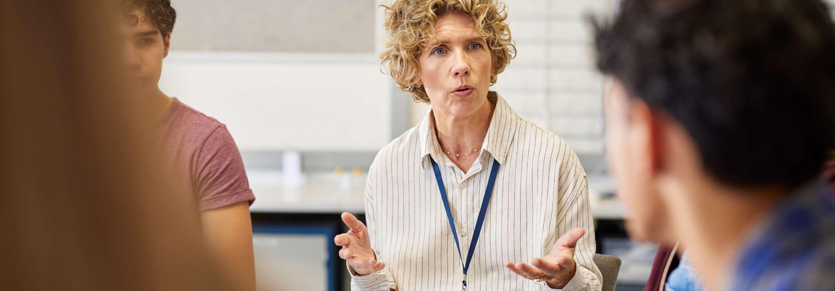 Patient financial counselor wearing a lanyard and sweater speaking to a group of people sitting in a circle