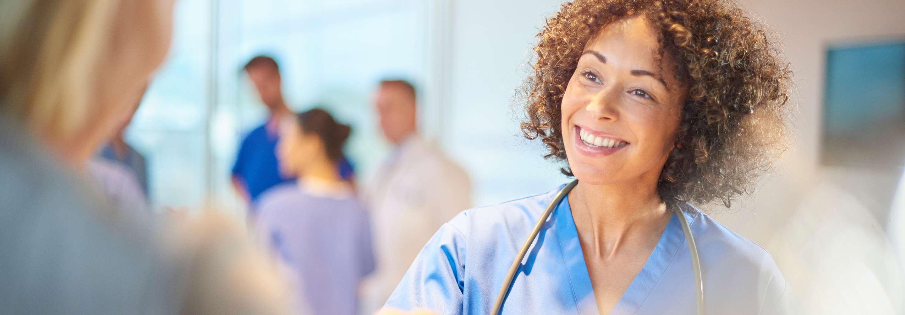 Manager of clinical operations nurse in blue scrubs shaking hands in the hospital corridor