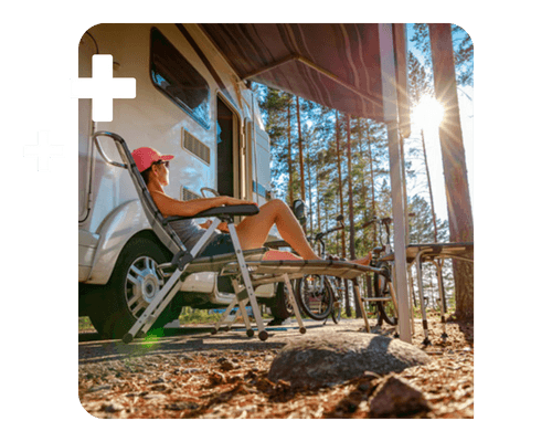 A woman relaxes in a lawn chair in the sun on front of her camper