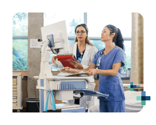 Two healthcare professionals reviewing patient data on a computer in a hospital setting.